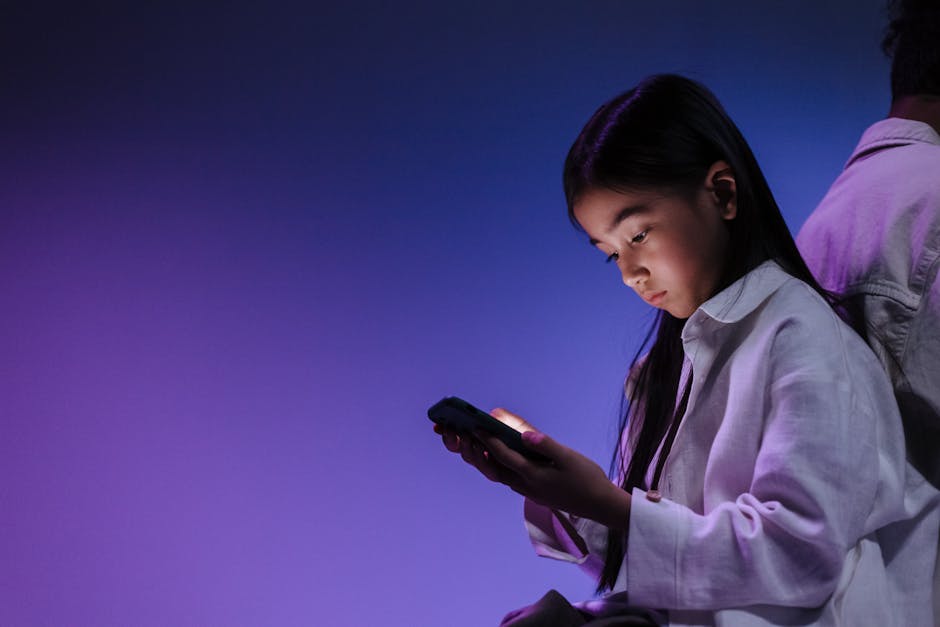 A girl using a smartphone under ambient blue and purple light.